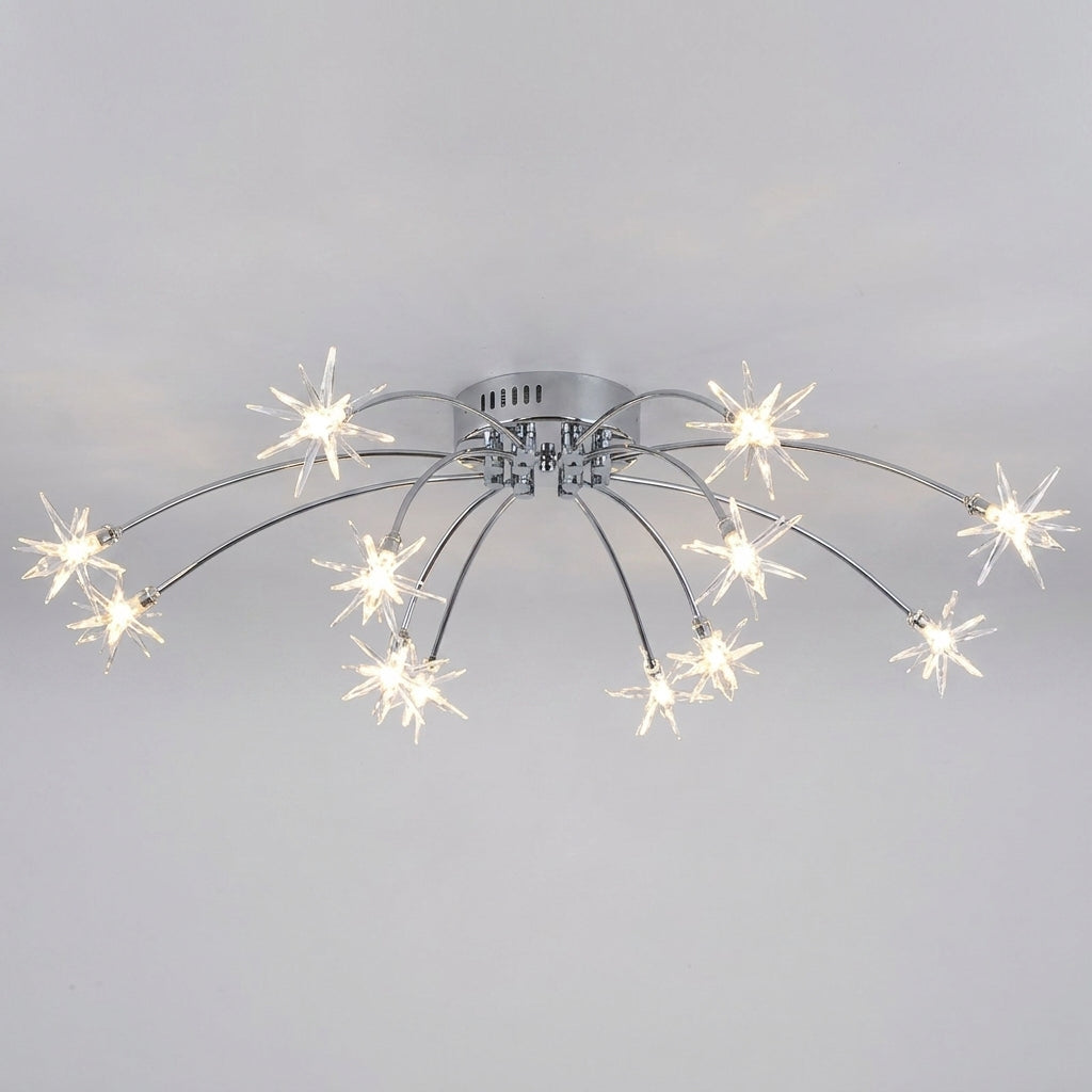A modern ceiling light fixture with a silver chrome base and multiple curved arms ending in star-shaped clear glass shades that glow with warm white light, shown against a plain light gray wall.