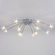 A modern ceiling light fixture with a silver chrome base and multiple curved arms ending in star-shaped clear glass shades that glow with warm white light, shown against a plain light gray wall.