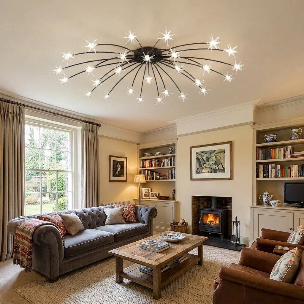 A modern multi-arm ceiling light fixture with starburst-shaped metal arms and glowing bulbs, mounted on the ceiling of a cozy living room with a grey sofa, wooden coffee table, and fireplace in the background.