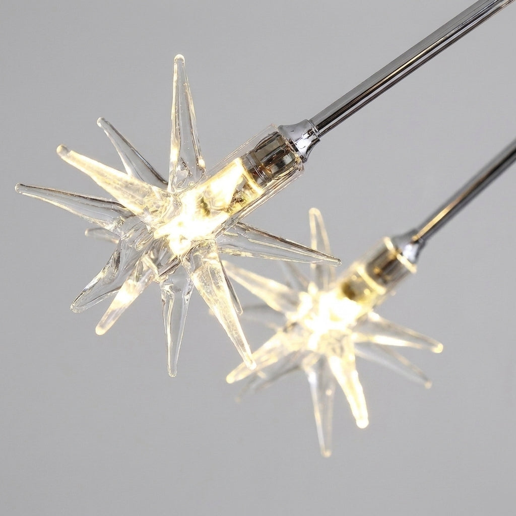 Clear star-shaped silqa lights with warm white illuminated bulbs against a plain light grey background.
