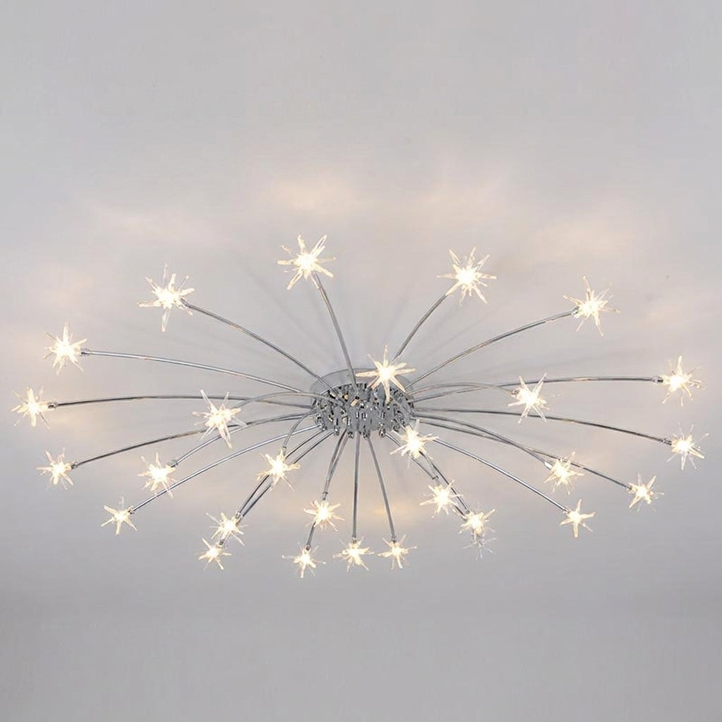 A modern ceiling light fixture with a silver chrome dandelion-inspired design, featuring multiple thin radiating arms ending in glowing warm white starburst bulbs, shown against a plain light grey ceiling.