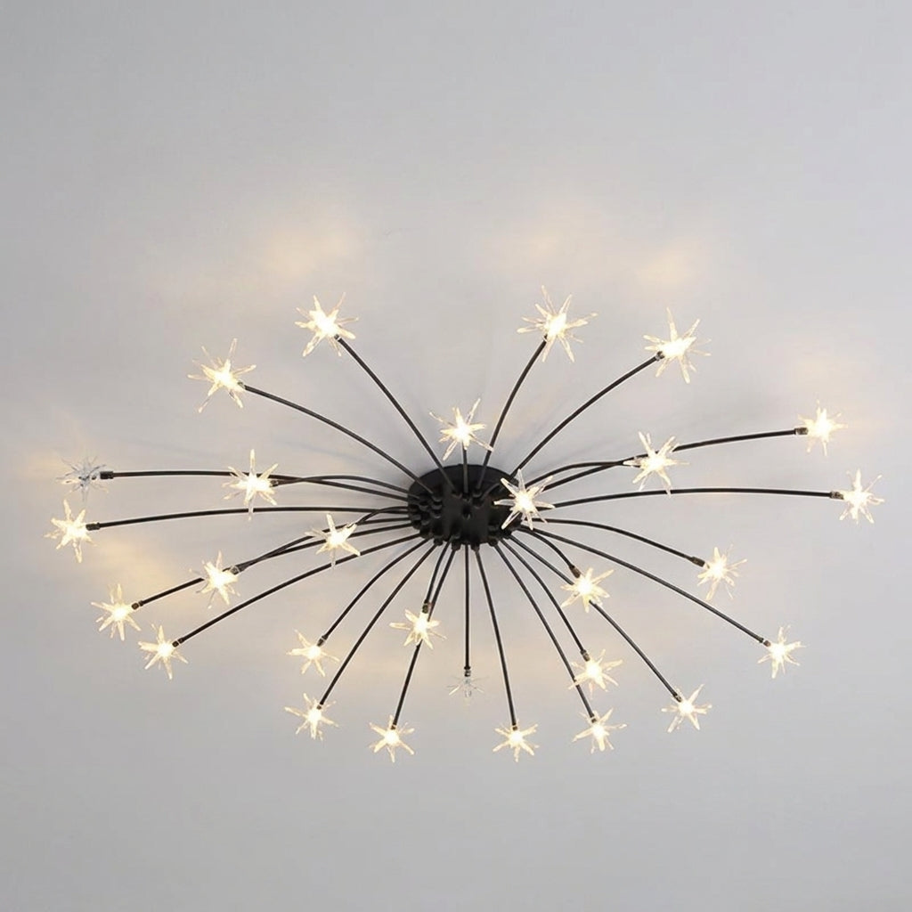 A modern ceiling light fixture with a black central hub and multiple thin radiating arms ending in small star-shaped bulbs that glow warm white, shown against a plain light grey wall.