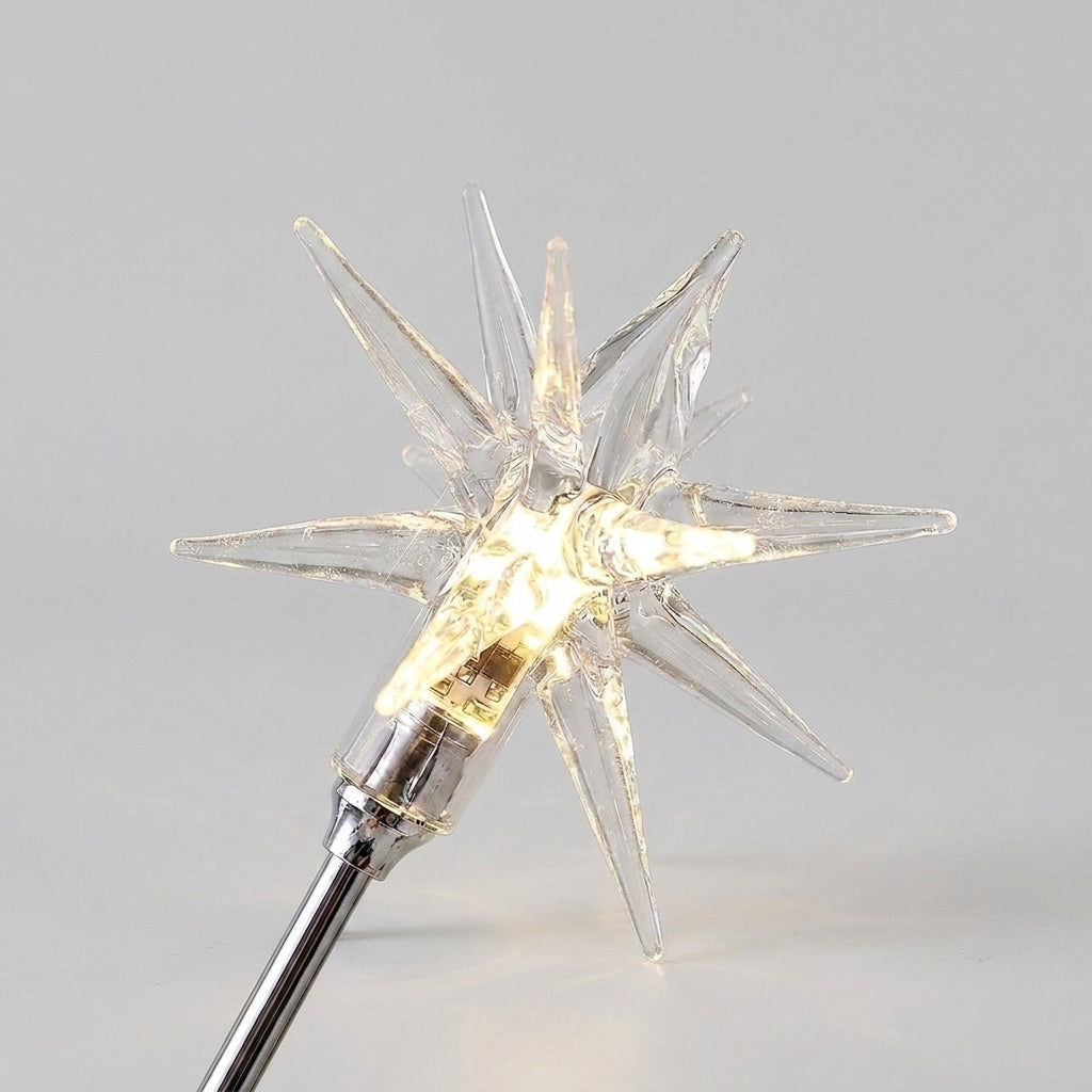 A clear glass star-shaped warm white LED light glowing from the centre, mounted on a silver metal chandelier arm, shown against a neutral light grey background.