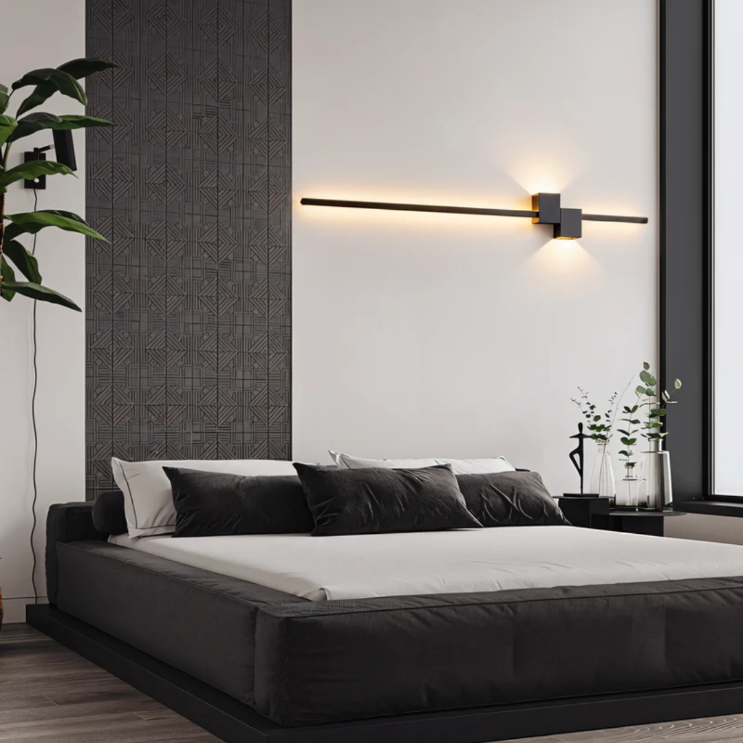 Black geometric aexi wall sconce mounted horizontally over a contemporary low-profile bed