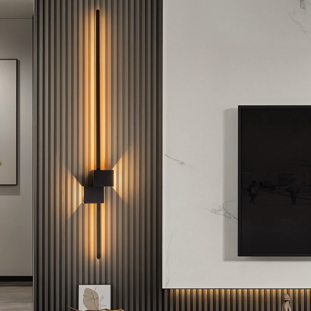 Vertical black linear aexi wall sconce installed on a slatted wood accent wall next to a television