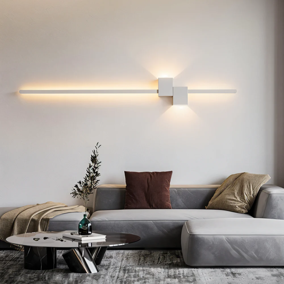 Modern white geometric linear aexi LED wall sconce mounted horizontally above a grey living room sofa