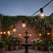Afqo solar string lights hanging along a brick garden wall above a stone fountain