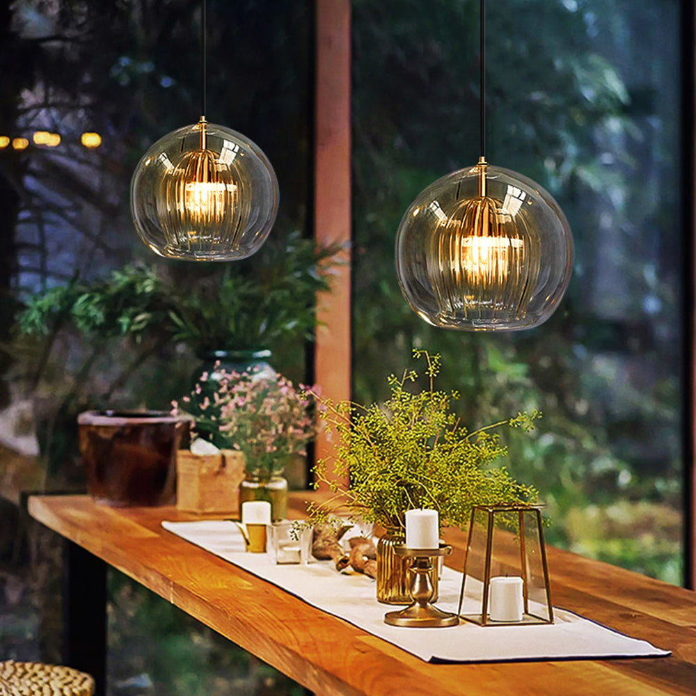 Pair of amber double-layer glass globe pendants illuminating a rustic wooden dining table