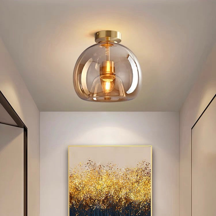 Amber glass globe compact ceiling light casting a warm glow above hallway artwork