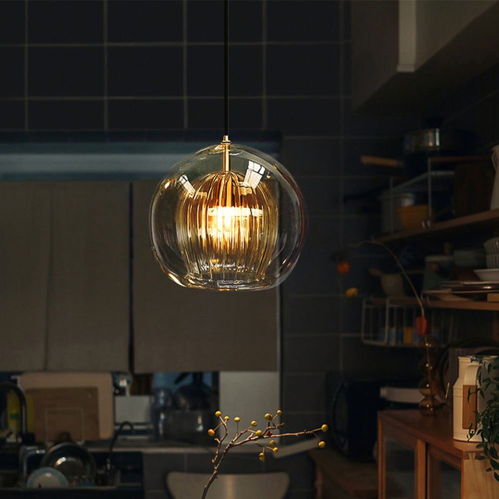 Warm amber glass globe pendant light adding a cosy ambience to a dark, modern kitchen setting