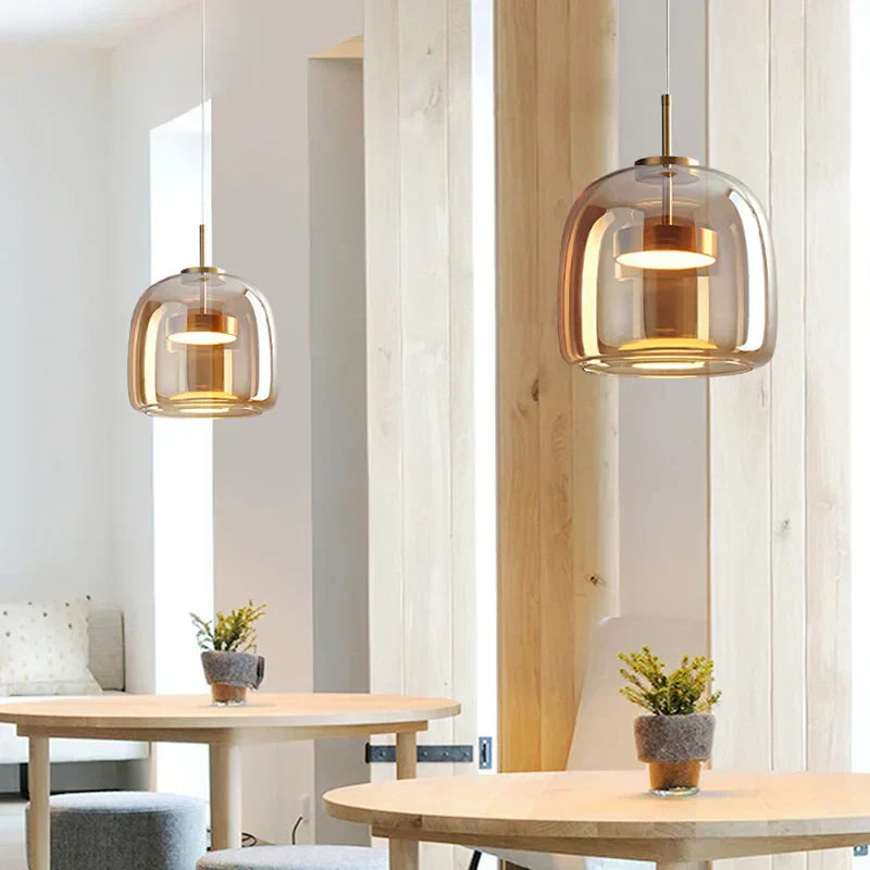 Two warm amber glass pendant lamps suspended over a light wood dining table