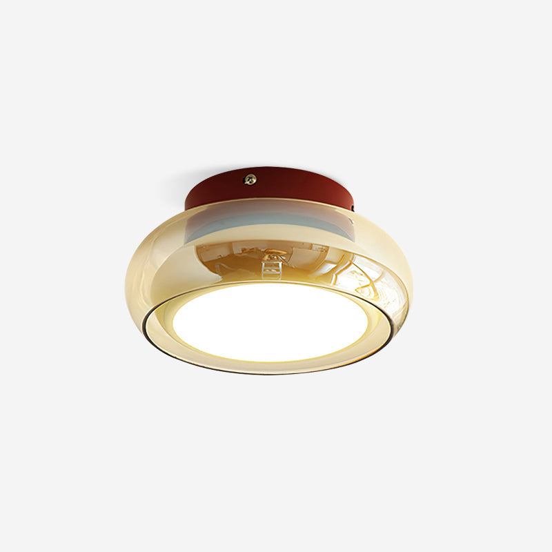 Amber tinted glass dome lamp with a red metal base glowing against a plain ceiling