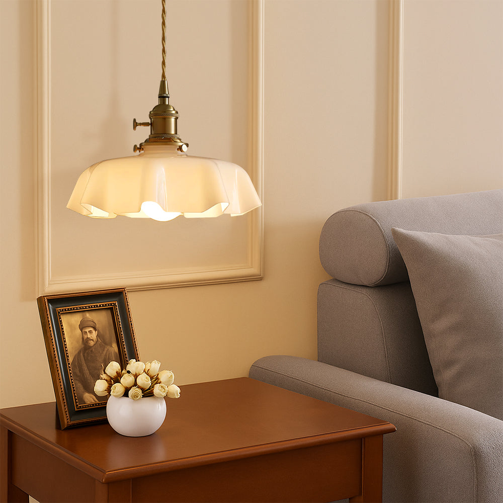 Antique brass scalloped pendant light illuminating a wooden side table next to a grey lounge sofa