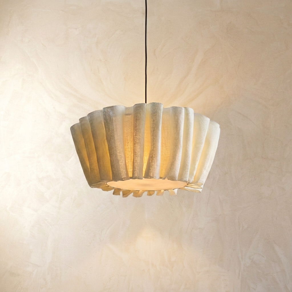 Japanese Wabi-Sabi pleated fabric aqer pendant light glowing warmly against a minimalist textured wall