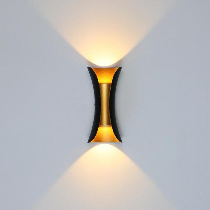 Architectural black and gold exterior wall sconce casting warm up and down illumination