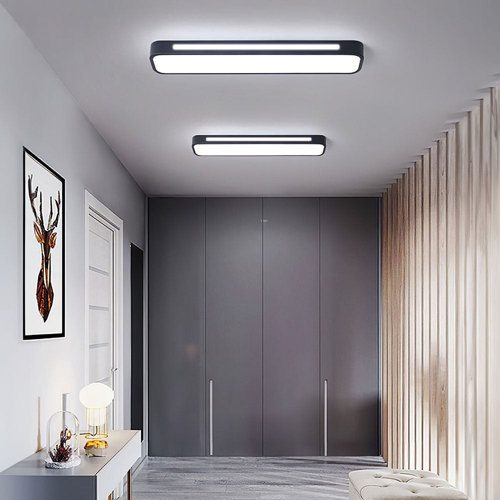 Two modern black linear LED flush mount atio ceiling lights illuminating a contemporary minimalist hallway