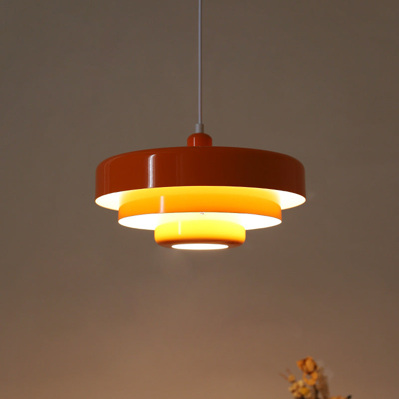 Illuminated orange tiered balel pendant light casting a warm, glare-free glow in a dark room