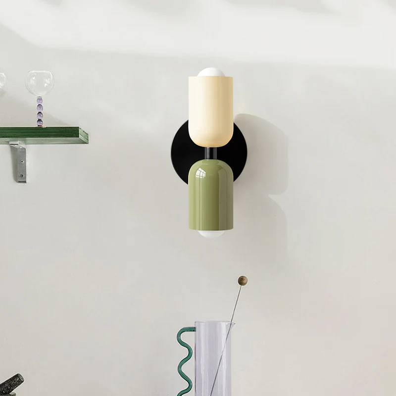 Front view of the beige and green mid-century capsule wall light illuminating a white wall