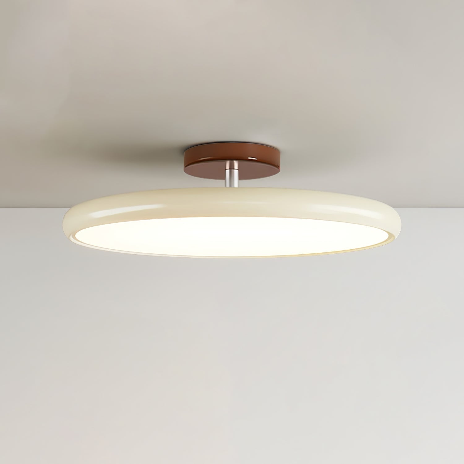 Beige tilting ceiling lamp installed on a white ceiling, angled downwards