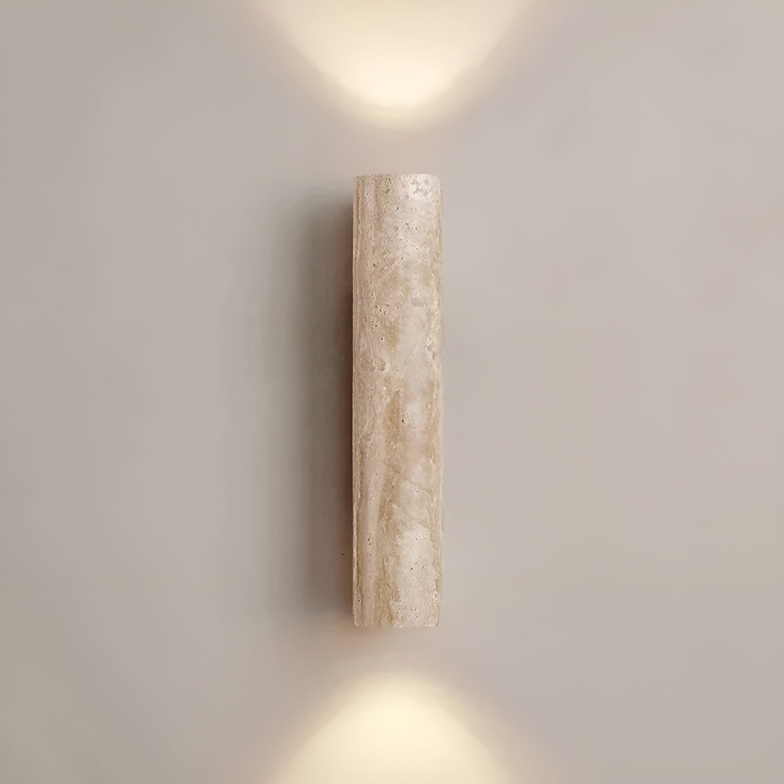Front view of the beige travertine cylindrical wall lamp providing elegant architectural lighting