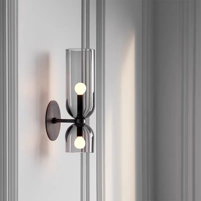 Illuminated bitlat grey glass double-head wall light casting a warm, ambient glow on a panelled interior wall