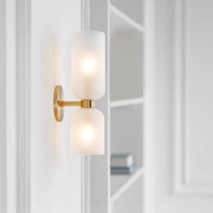 White opaque bitlat glass hourglass wall sconce providing soft, glare-free ambient light near a modern bookshelf