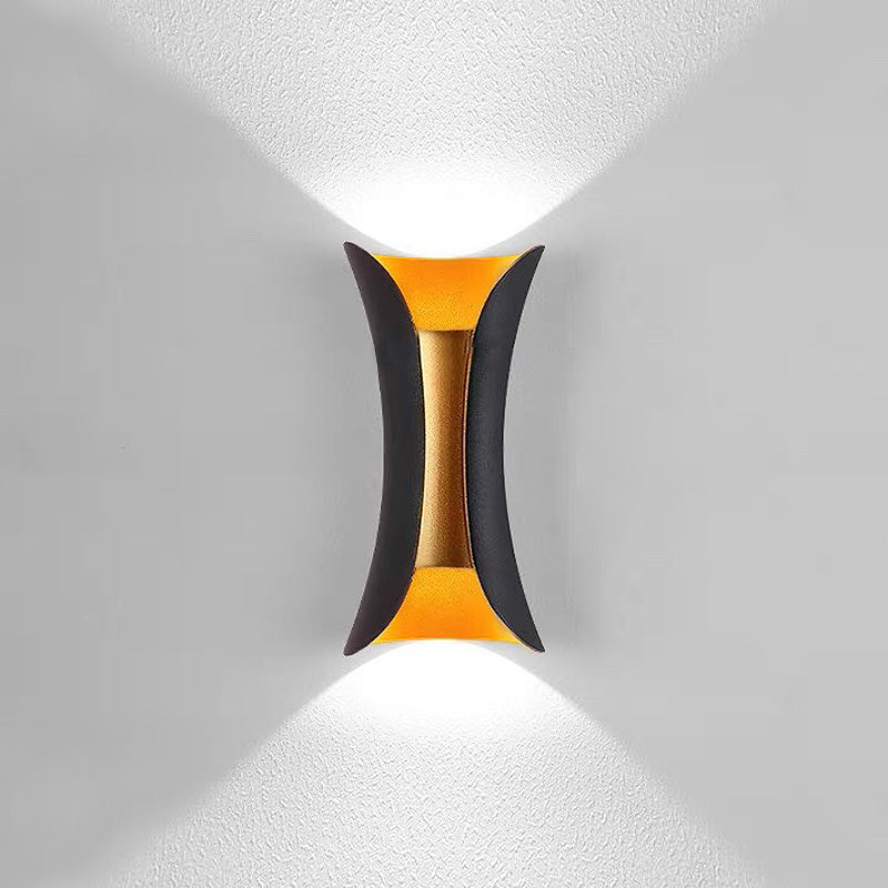 Front view of the illuminated black and gold two-tone architectural outdoor sconce