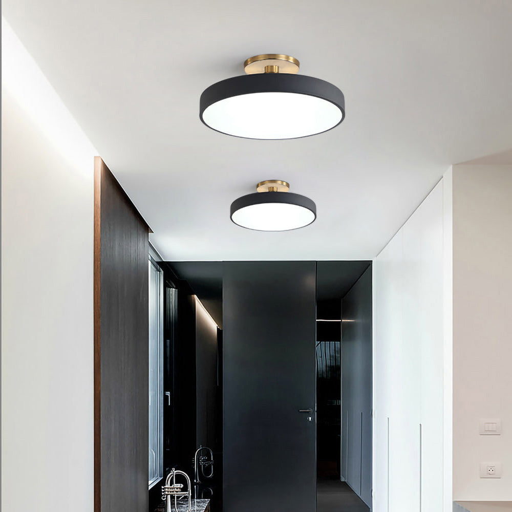 Pair of black circular ceiling fixtures providing bright illumination in a modern dark hallway