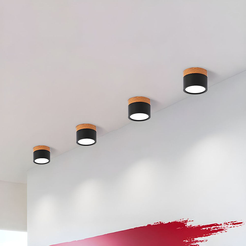 Row of black cylinder flush ceiling lights acting as wall accent lighting