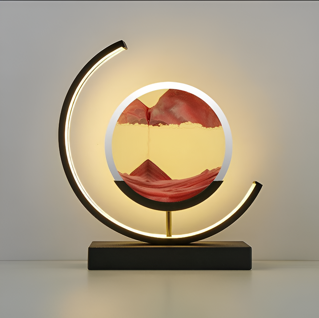 Front view of the black circular LED table lamp showcasing flowing orange sand art