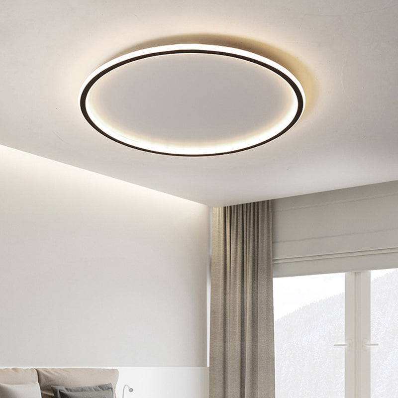 Black halo LED flush mount ceiling light providing a bright ambient glow in a modern bedroom