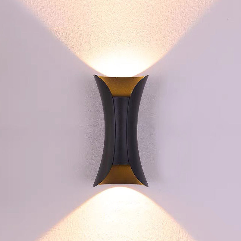 Minimalist black hourglass LED outdoor wall light providing an even wall washing glow