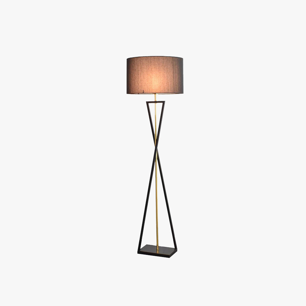 Isolated view of the black hourglass metal floor lamp featuring a warm illuminated fabric drum shade