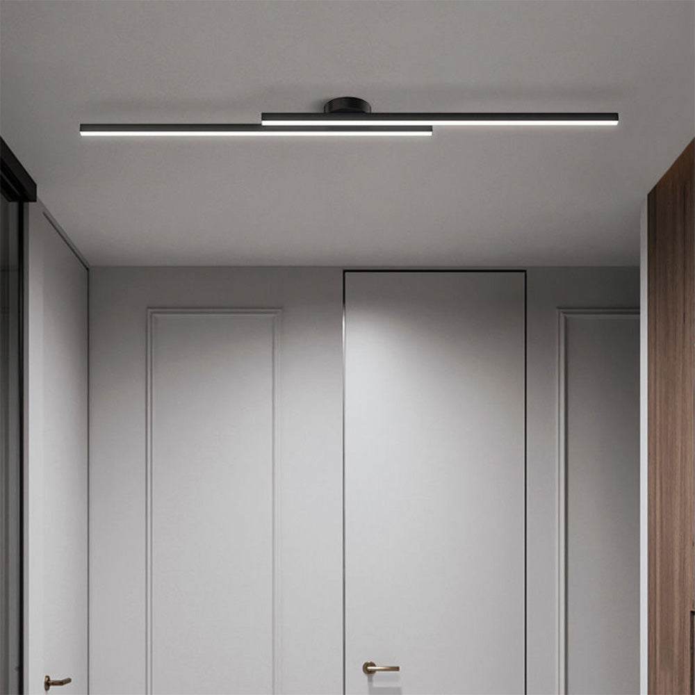 Black minimalist linear ceiling light illuminating a bright, modern white hallway