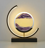 Modern LED moving sand art table lamp featuring a black circular frame and flowing purple sand