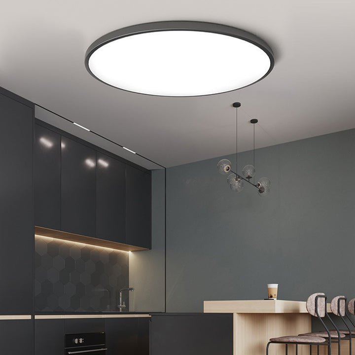 Modern black round LED ceiling lamp providing sleek overhead lighting in a dark modern kitchen