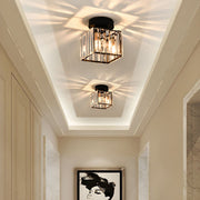 Two modern black square crystal prism flush mount ceiling lights illuminating a bright hallway with a starburst pattern