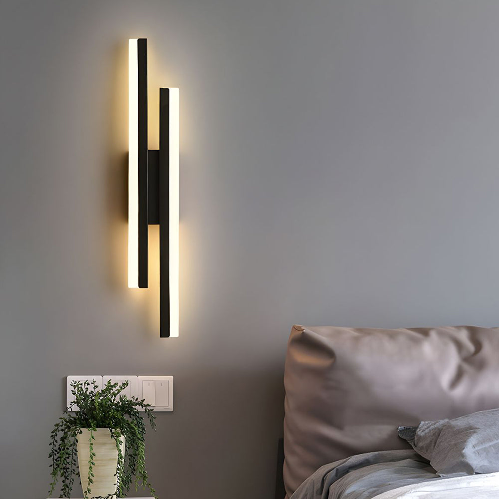 Black staggered LED wall lamp mounted vertically as a modern, space-saving bedside light