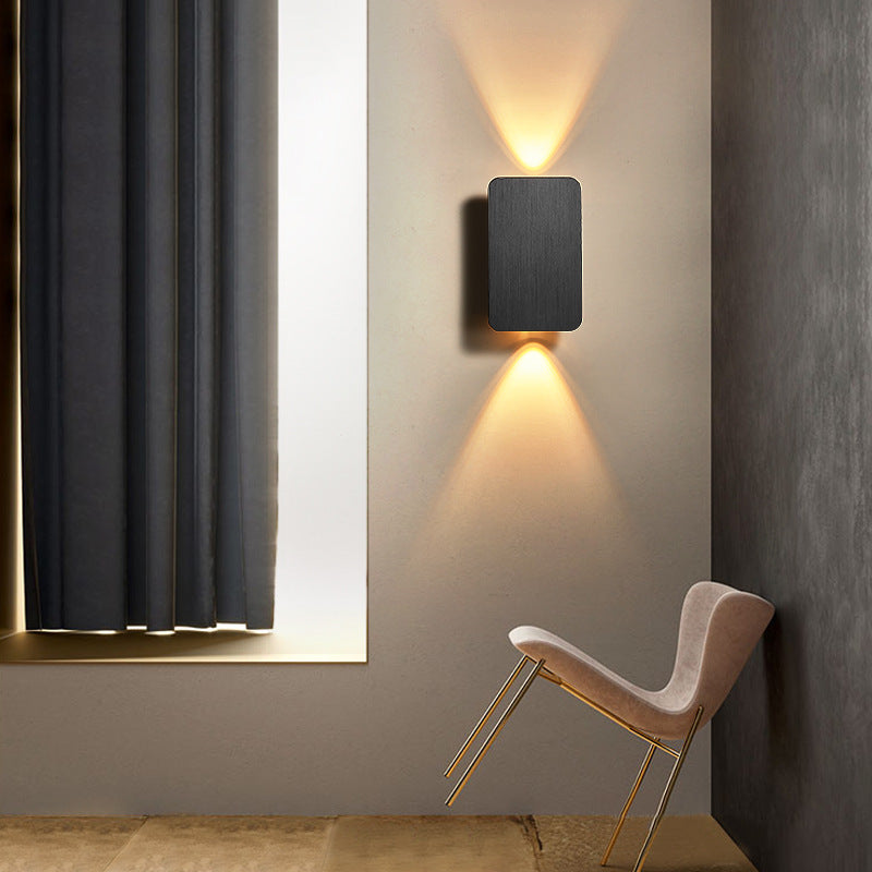 Black up and down lighting rectangular wall sconce illuminating a sleek, modern reading corner
