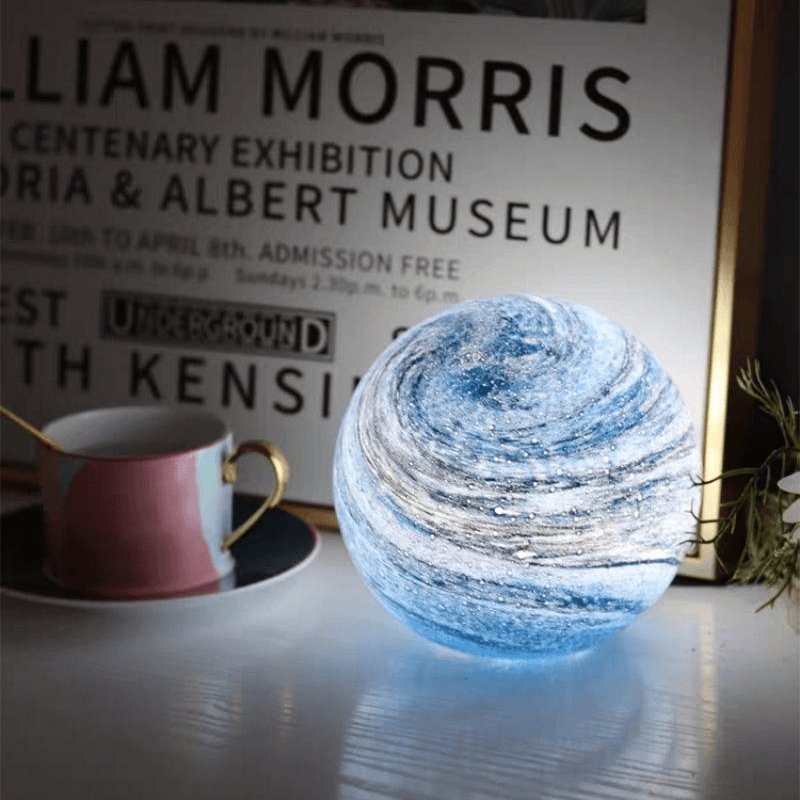 Blue marbled glass sphere acting as a beautiful desk decor accent next to a framed poster and coffee mug