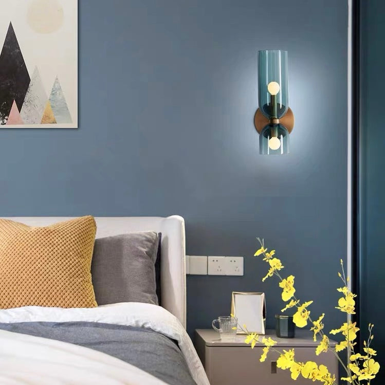 Blue mid-century modern glass wall sconce installed above a bedside table in a moody blue bedroom