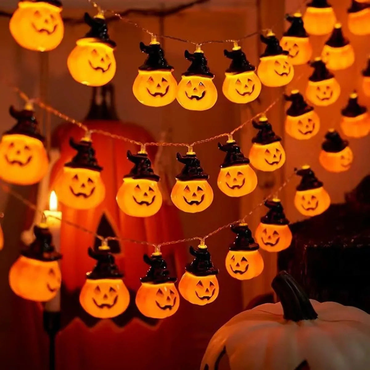 Brimsparks pumpkin-shaped LED string lights glowing in a cosy candlelit room with a large pumpkin decoration