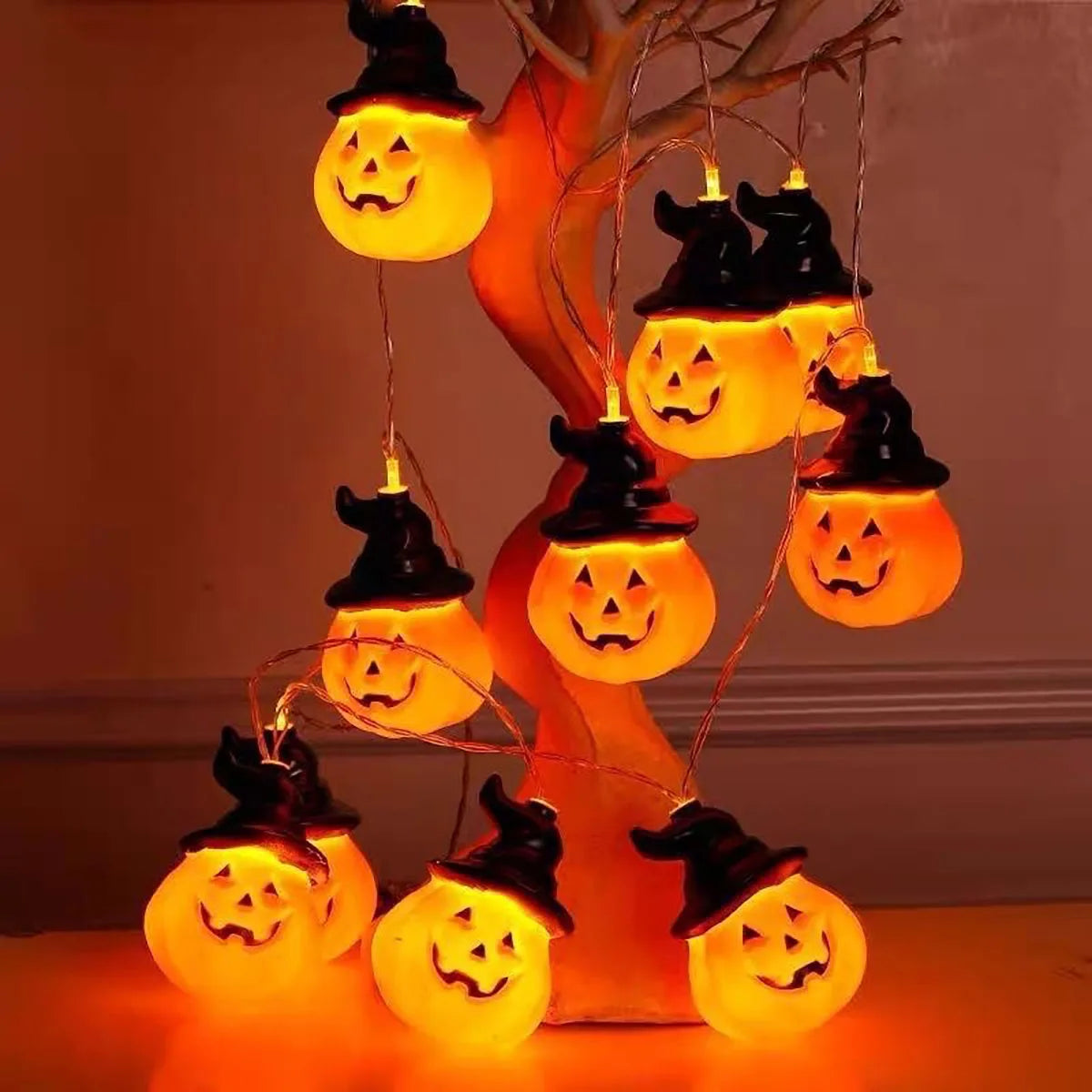 Brimsparks pumpkin-shaped LED string lights draped over a decorative bare-branch tree prop