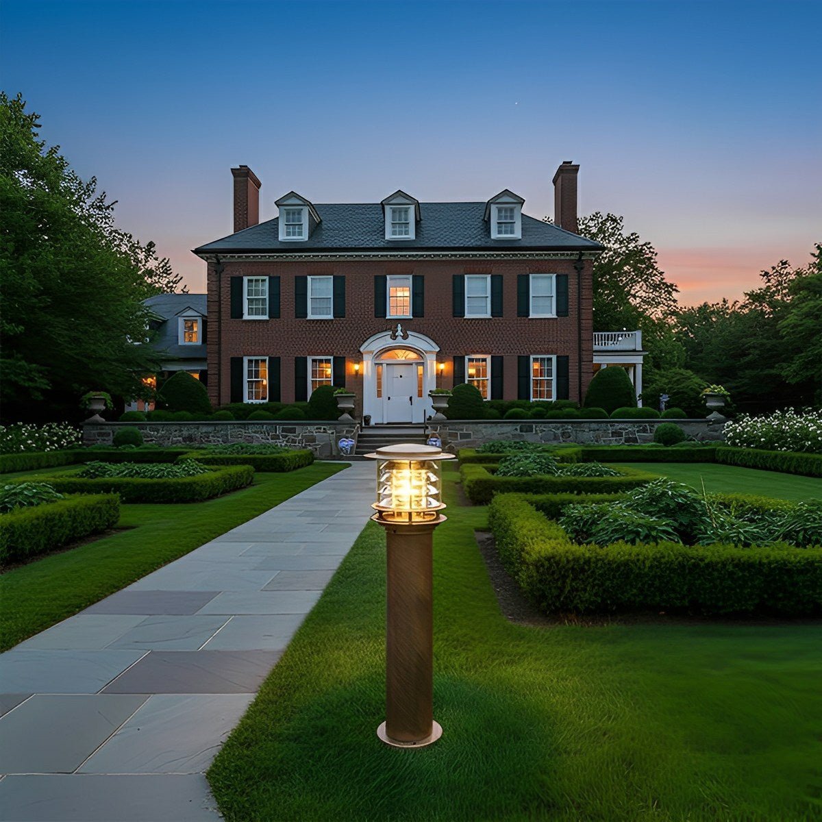 Bronze outdoor driveway bollard light centred on an elegant estate lawn at dusk