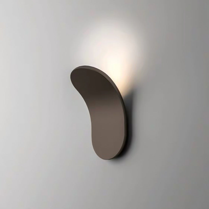 Close-up of a brown Nordic shield wall lamp casting a warm ambient glow on a plain wall