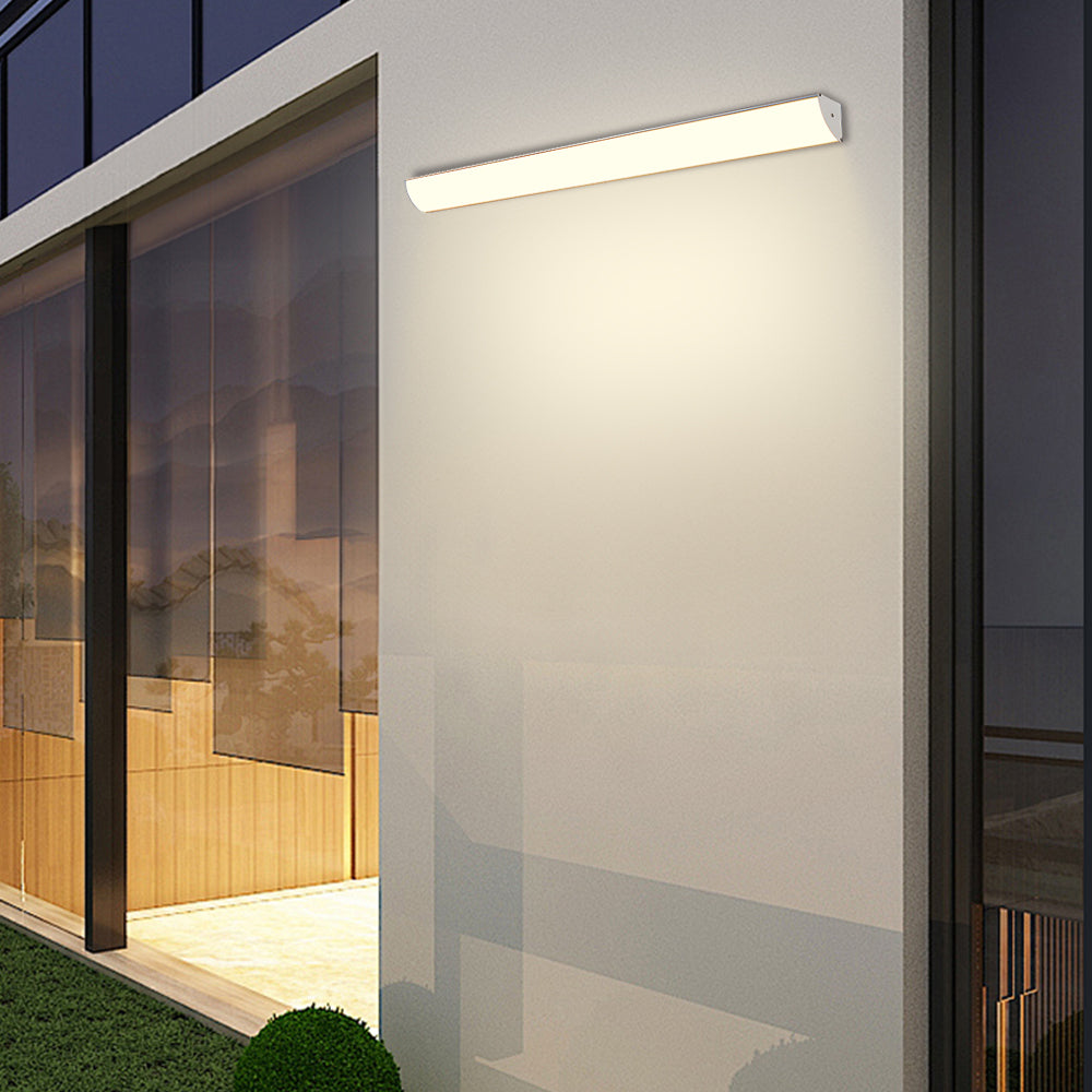 Minimalist front-lit bubce outdoor LED sconce glowing warmly on a textured grey wall