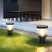 Pair of modern black bulba solar bollard lights illuminating the edge of a patio and lawn at night