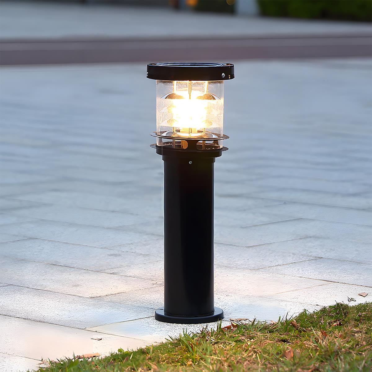 bulba tall black architectural bollard light illuminating a modern paved walkway at twilight