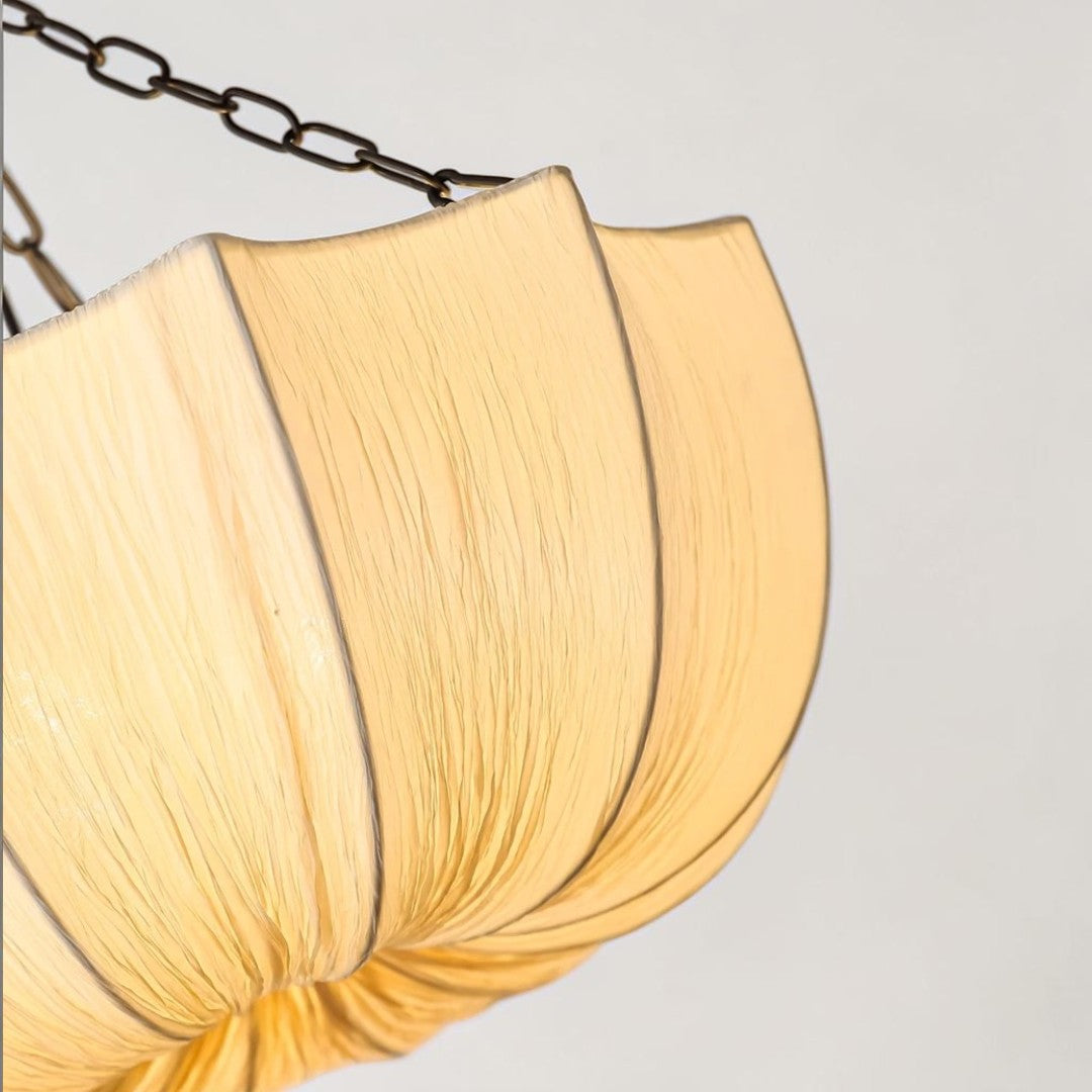 Buvla pleated fabric pendant light lit, warm glow, angled view