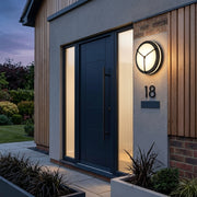 Byrzi outdoor LED wall light with triangle cutout beside a modern house entrance